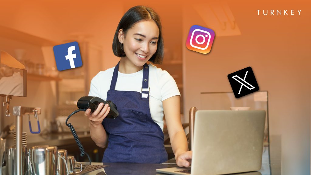 Woman looking at her laptop while holding a pos system trying to integrate the pos system with social media for marketing